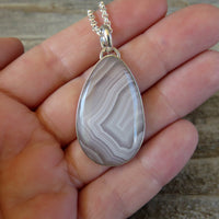 White lace agate and sterling silver pendant on hand